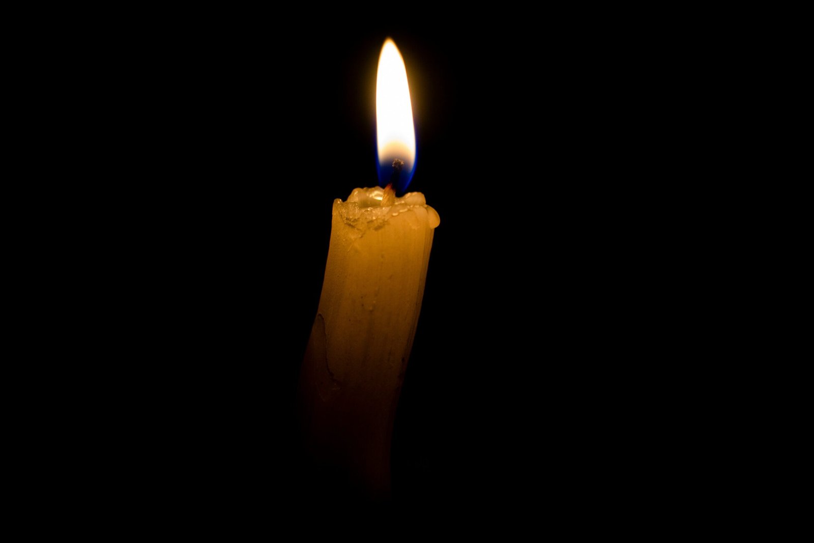 a lit candle in the dark with a black background